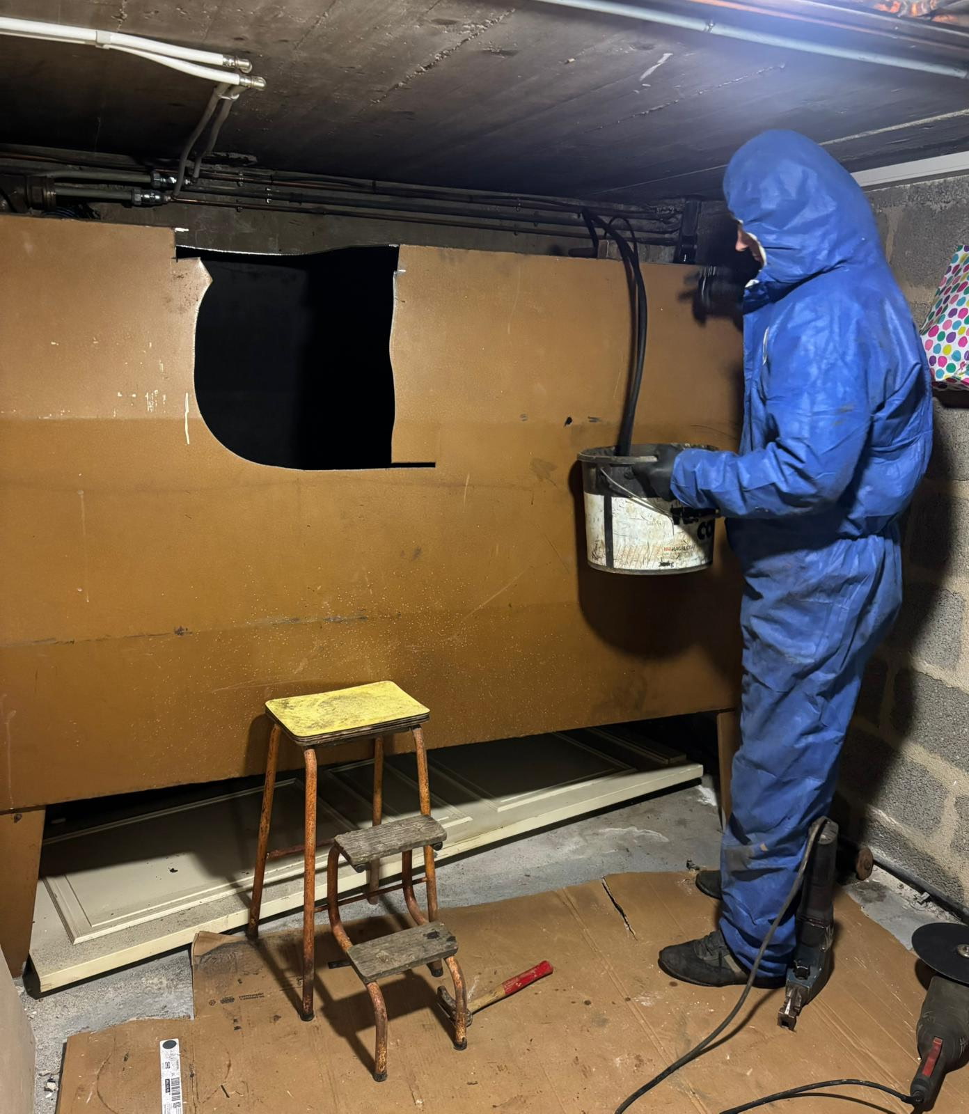 Technicien opérant durant l'aspiration des boues avant la phase de dégazage de la citerne à fioul partiellement découpée