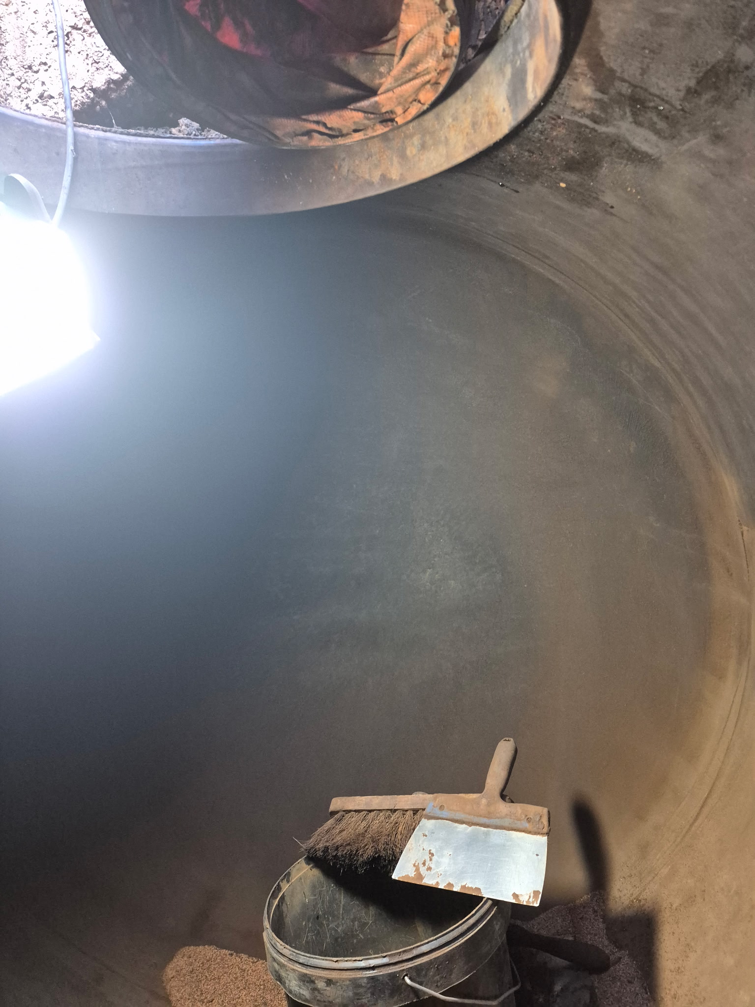 La cuve à fioul vue de l'intérieur durant la phase de nettoyage : en haut, le trou d'homme permet l'insertion du tuyau de ventilation pour le dégazage.