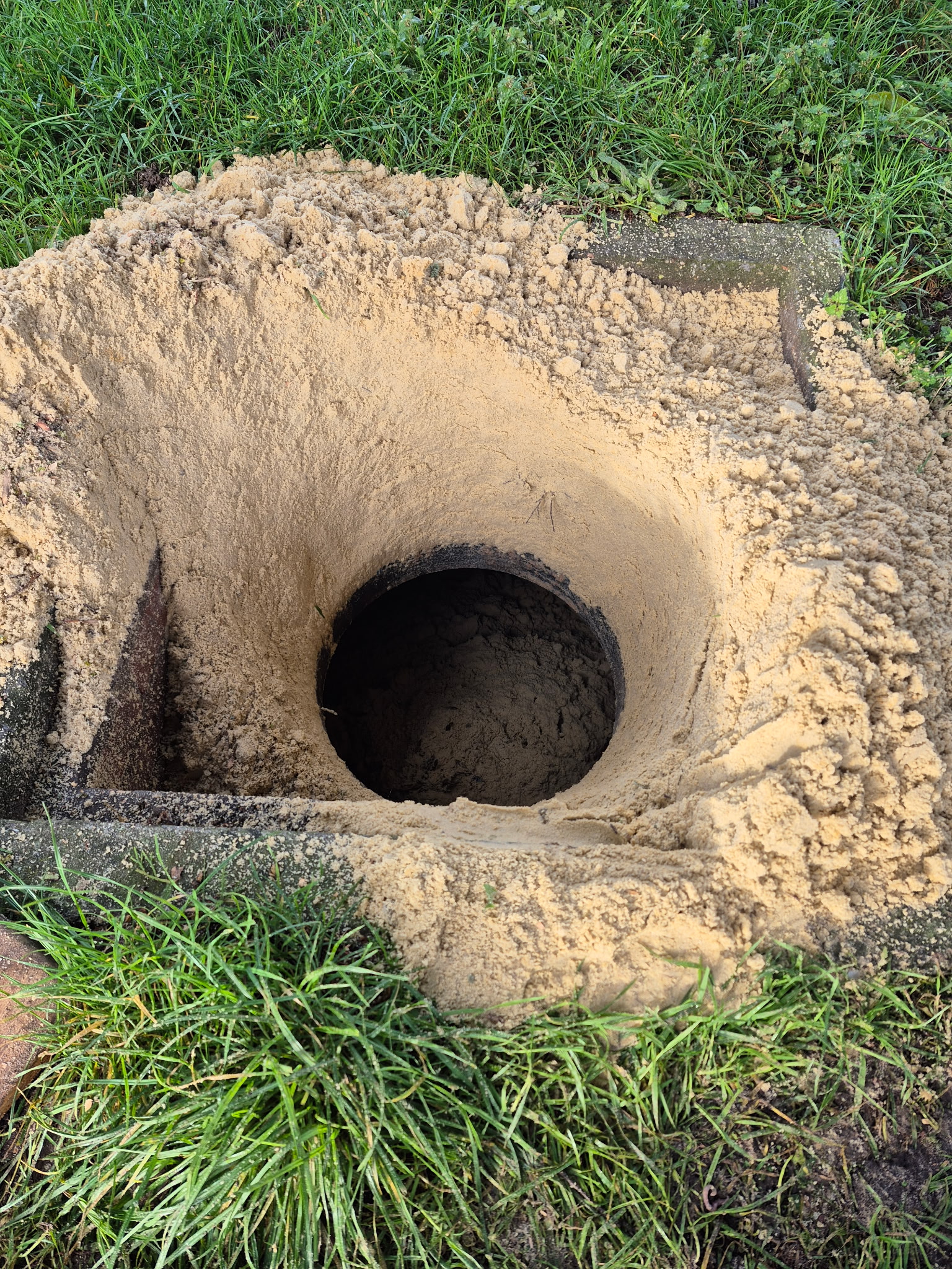 Neutralisation au sable d'une cuve à fioul enterrée par le regard d'accès au niveau du sol.